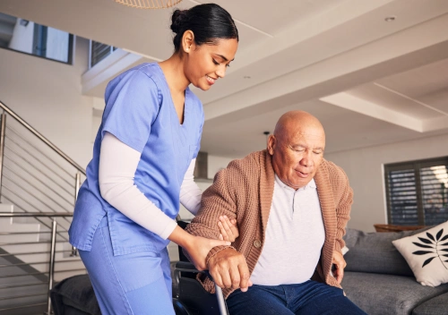 Medical assistant helping senior man stand with cane